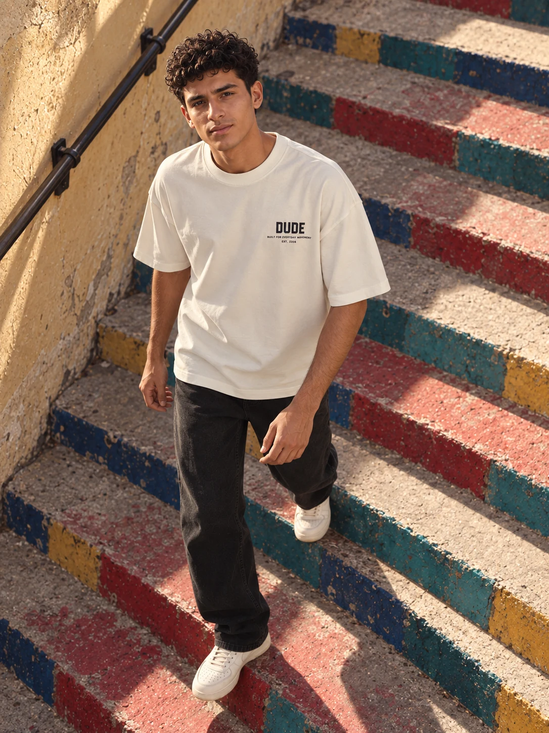 Model descending the colorful steps in a white DUDE T-shirt