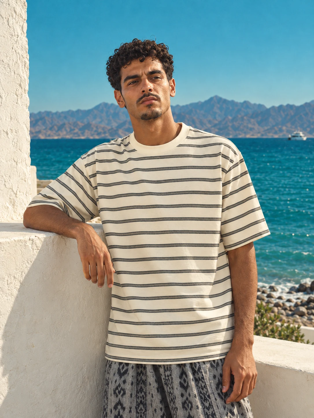 Getwinn striped T-shirt portrait against a white wall and turquoise sea