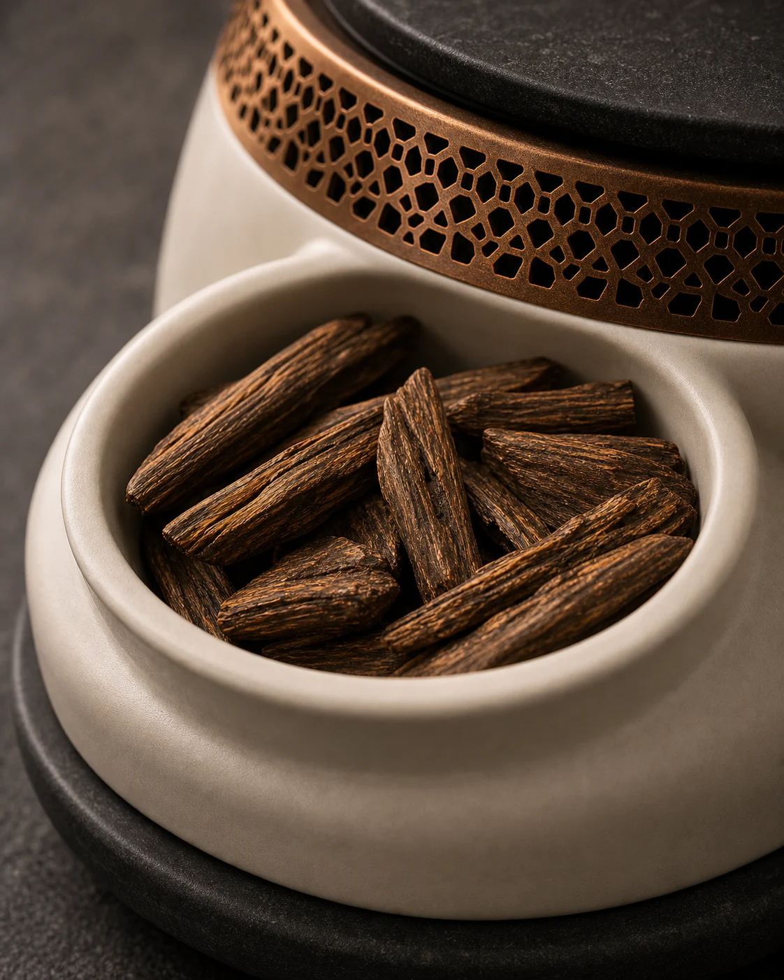 Macro study of oud wood, warm porcelain, aged copper, and basalt materials for EMBERA