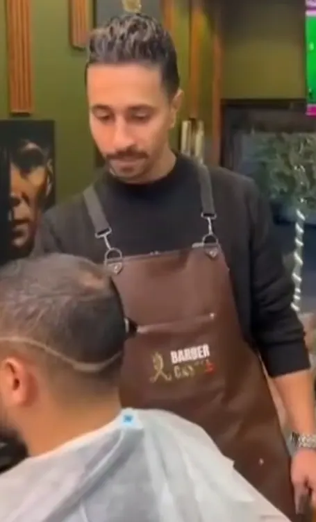 Source video frame of a Barber Castle barber working beside a client
