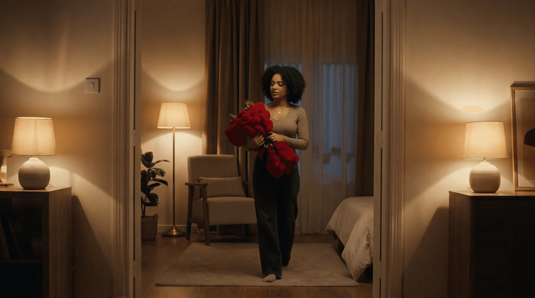 Woman carrying red roses through a warmly lit bedroom in the Bloom Corner brand film