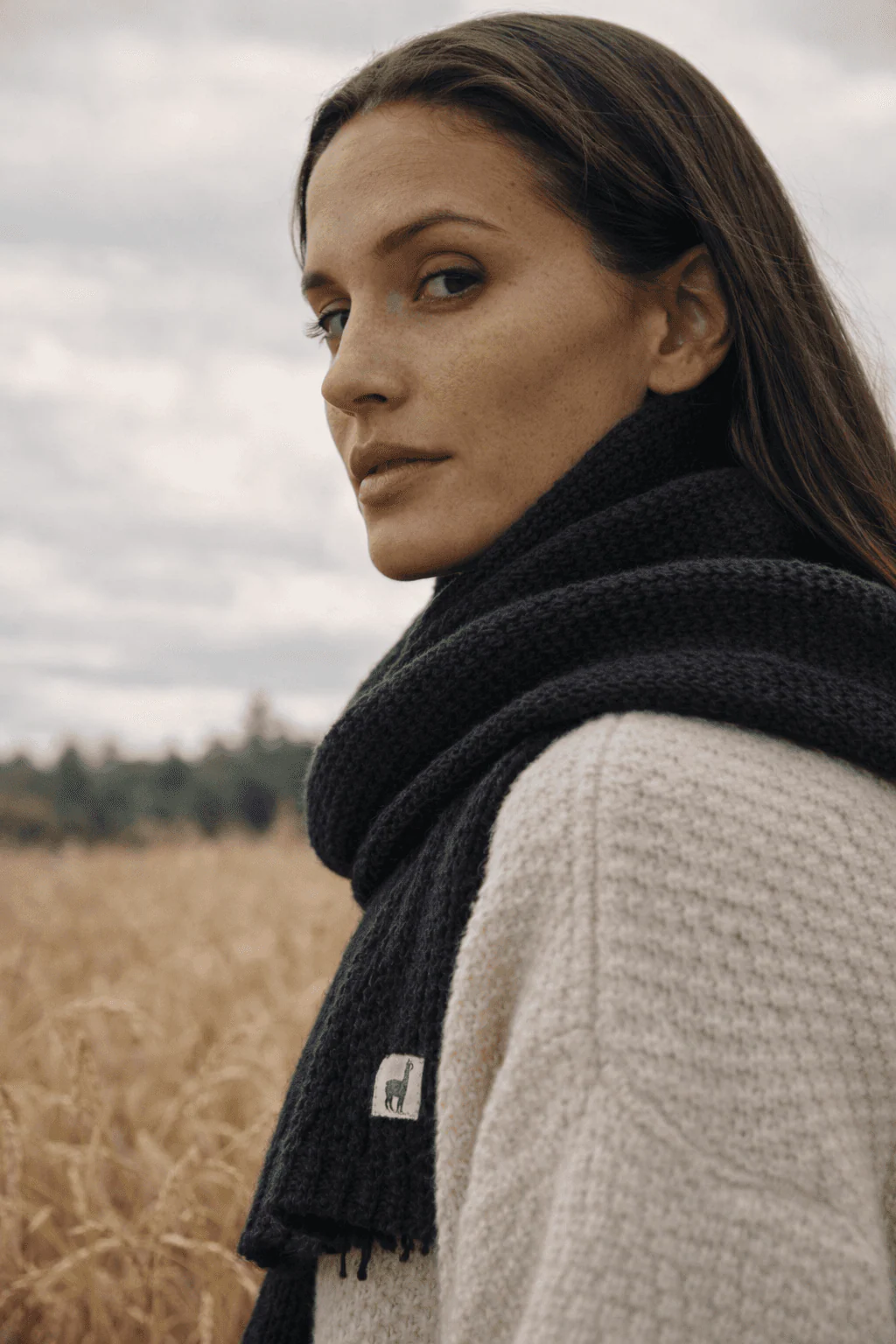 Portrait of a woman wearing the black Pokoloko scarf in a wheat field