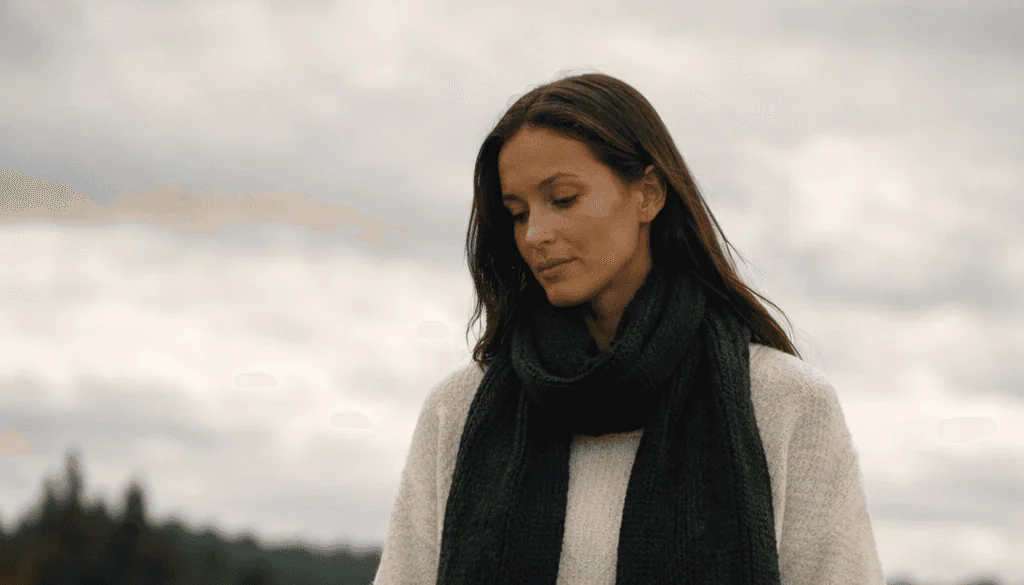 Woman wearing a black Pokoloko scarf in a field beneath an overcast sky