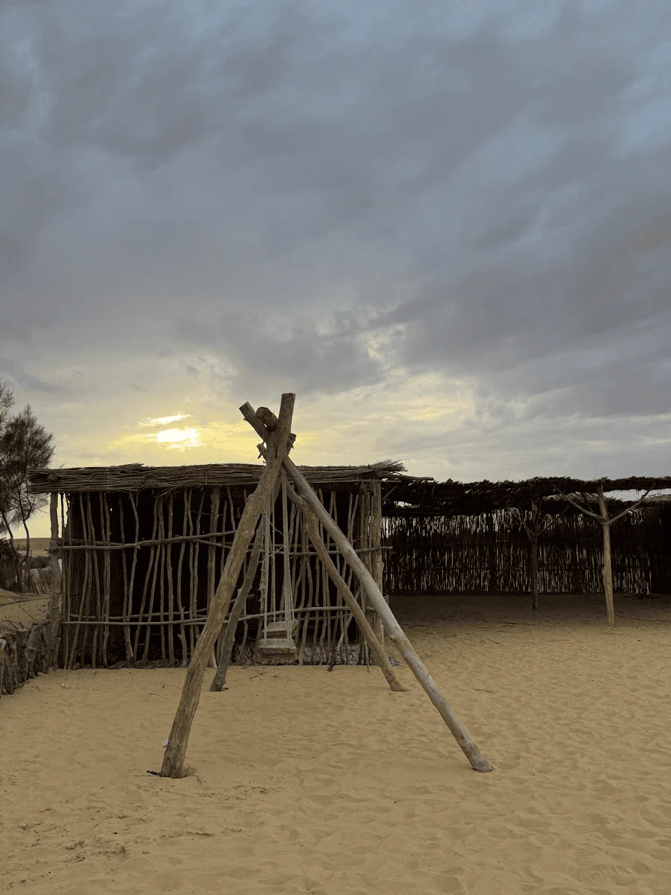 Wooden beach swing beneath a cloudy sunset sky
