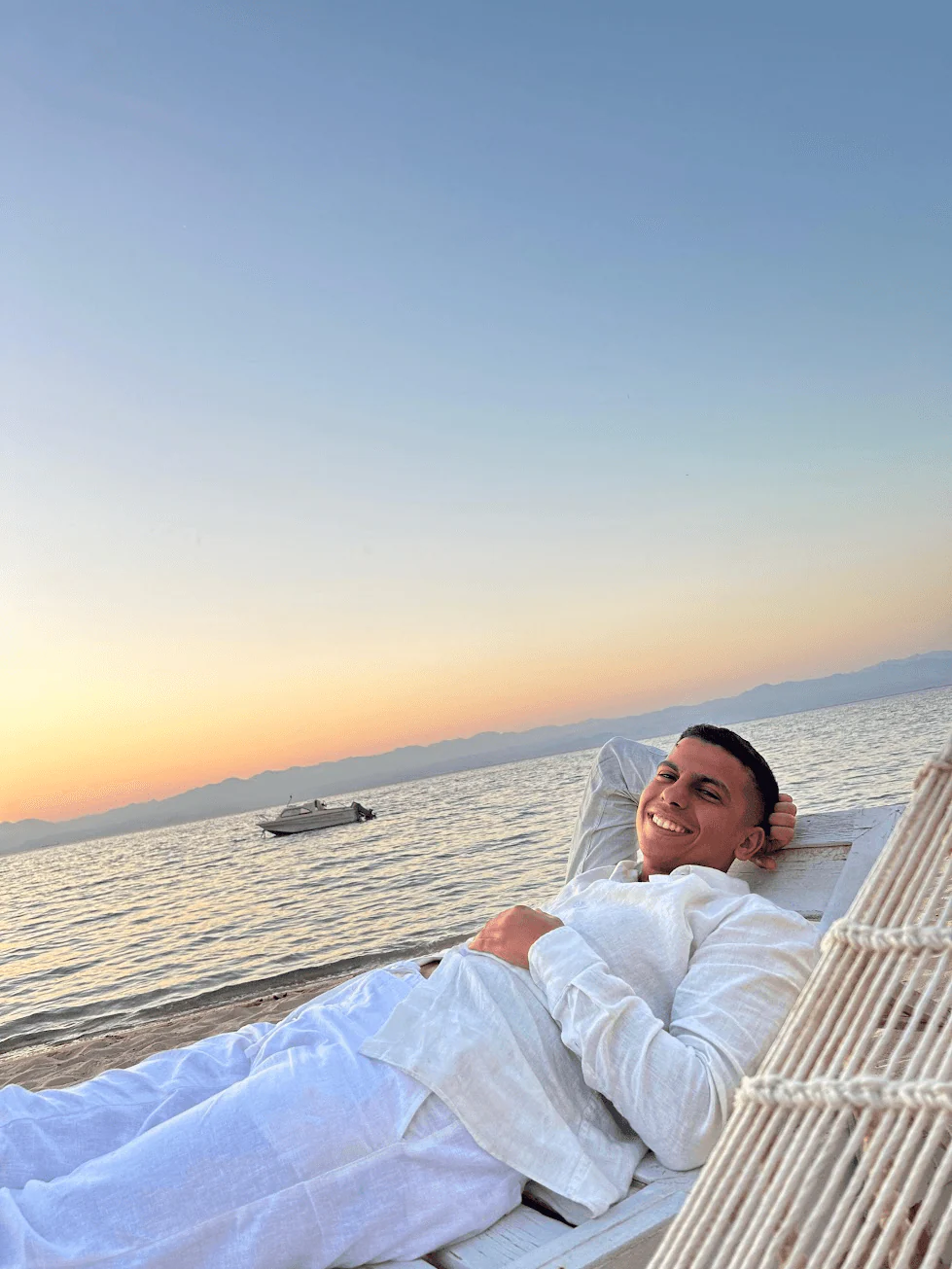 Mohamed Solyman relaxing in a seaside hammock at sunset