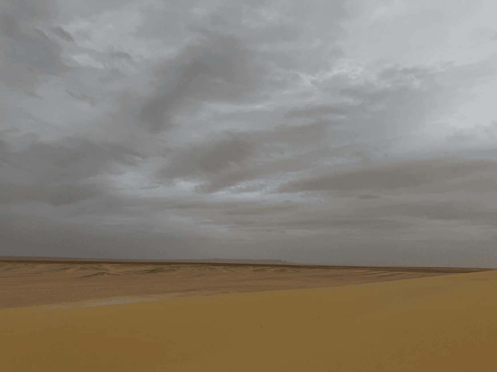 Open desert landscape beneath layered storm clouds