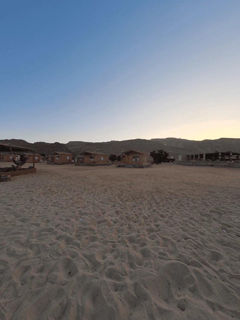 Desert camp cabins surrounded by mountains at sunset