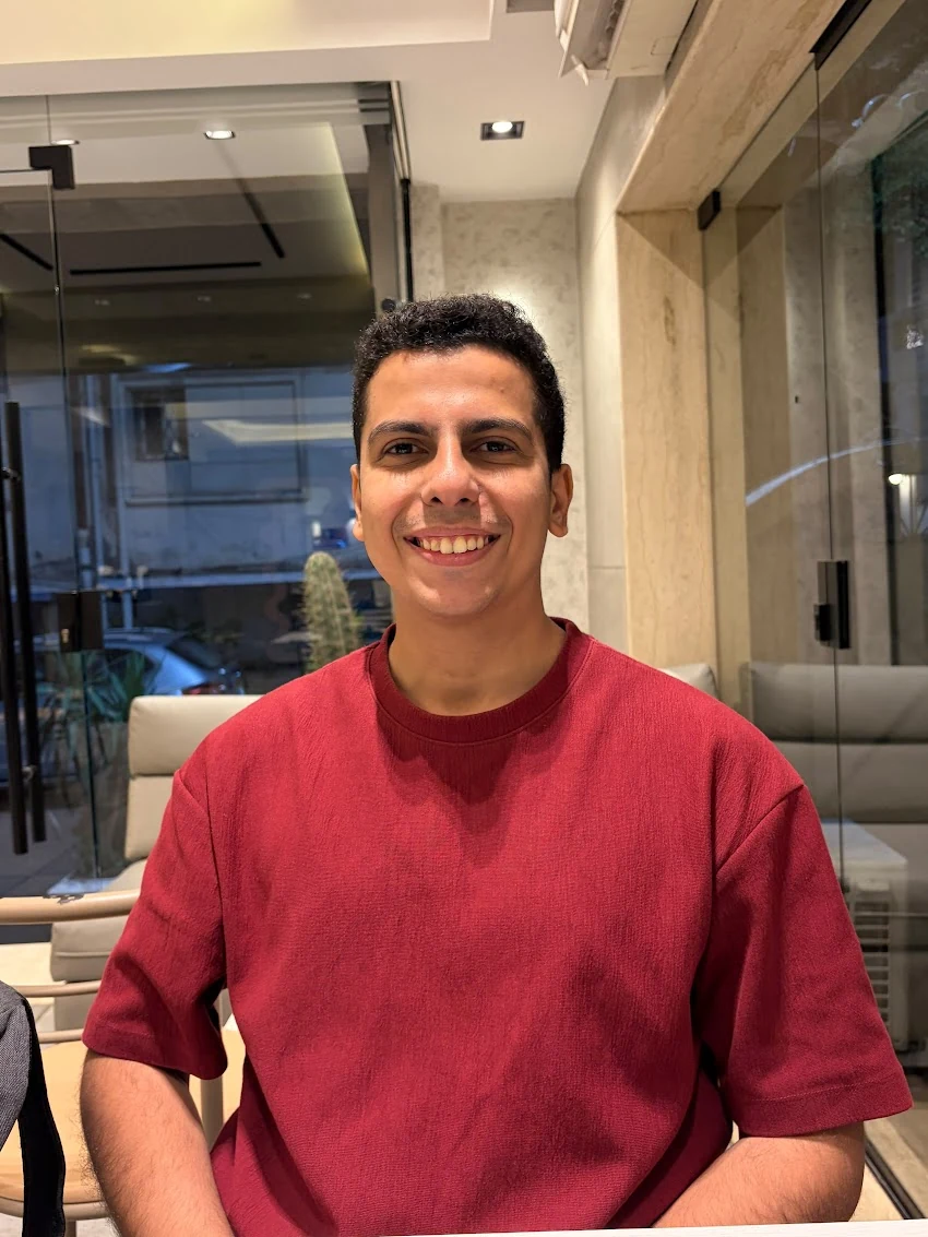 Mohamed Solyman smiling in a red shirt indoors